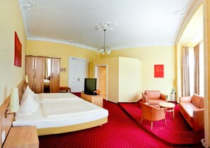 Een hotelkamer met een bed, een televisie, een bureau, een stoel en een bank.