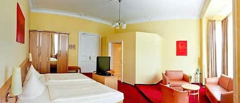 A hotel room with two beds, a television, a sofa, and a red carpet.