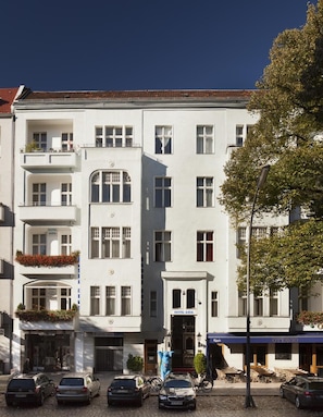 Ett hotell med flera våningar, balkonger, en restaurang på markplan och en parkeringsplats.
