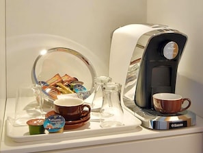 Una cafetera, una taza, un vaso y un envase con leche para café sobre una bandeja.