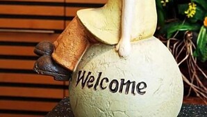 A figurine of a person sitting on a globe with the word 'Welcome' on it. - Hotel Ludwig Superior (Cologne)