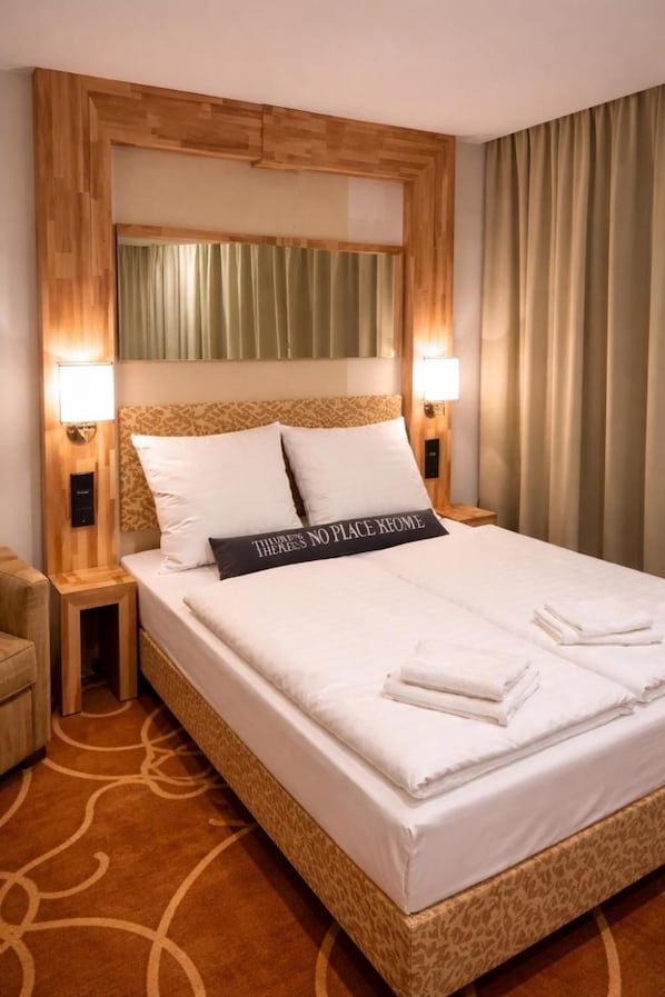 Une chambre d’hôtel avec un grand lit, deux lampes de chevet, une tête de lit ornée d’un panneau en bois et un panneau indicateur posé sur le lit.
