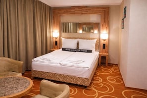 Une chambre d’hôtel avec un lit, une chaise, une petite table et un miroir.