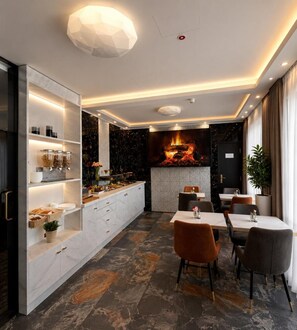 Un espace de restauration moderne doté d’une cheminée centrale, d’un comptoir de buffet et de différents types de sièges.