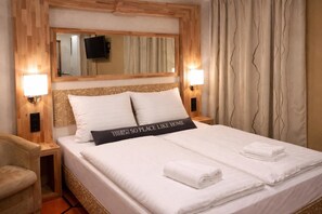 Une chambre d’hôtel avec un lit, deux lampes de chevet, un téléviseur à écran plat et un oreiller orné d’un motif.
