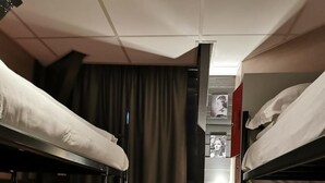 A compact room with bunk beds, a radiator, and a curtain. - Hotel Mevlana (Amsterdam)