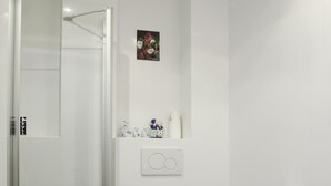 A compact bathroom with a glass shower enclosure, a white toilet, and a sink. - Hotel Mevlana (Amsterdam)