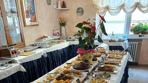 Une table de buffet garnie de divers plats, un vase rempli de fleurs et une fenêtre ornée de plantes.