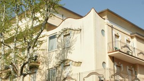 Un hôtel avec une enseigne indiquant « Hôtel Verudella », un panneau de signalisation pour le parking et des balcons aménagés avec du mobilier d’extérieur.
