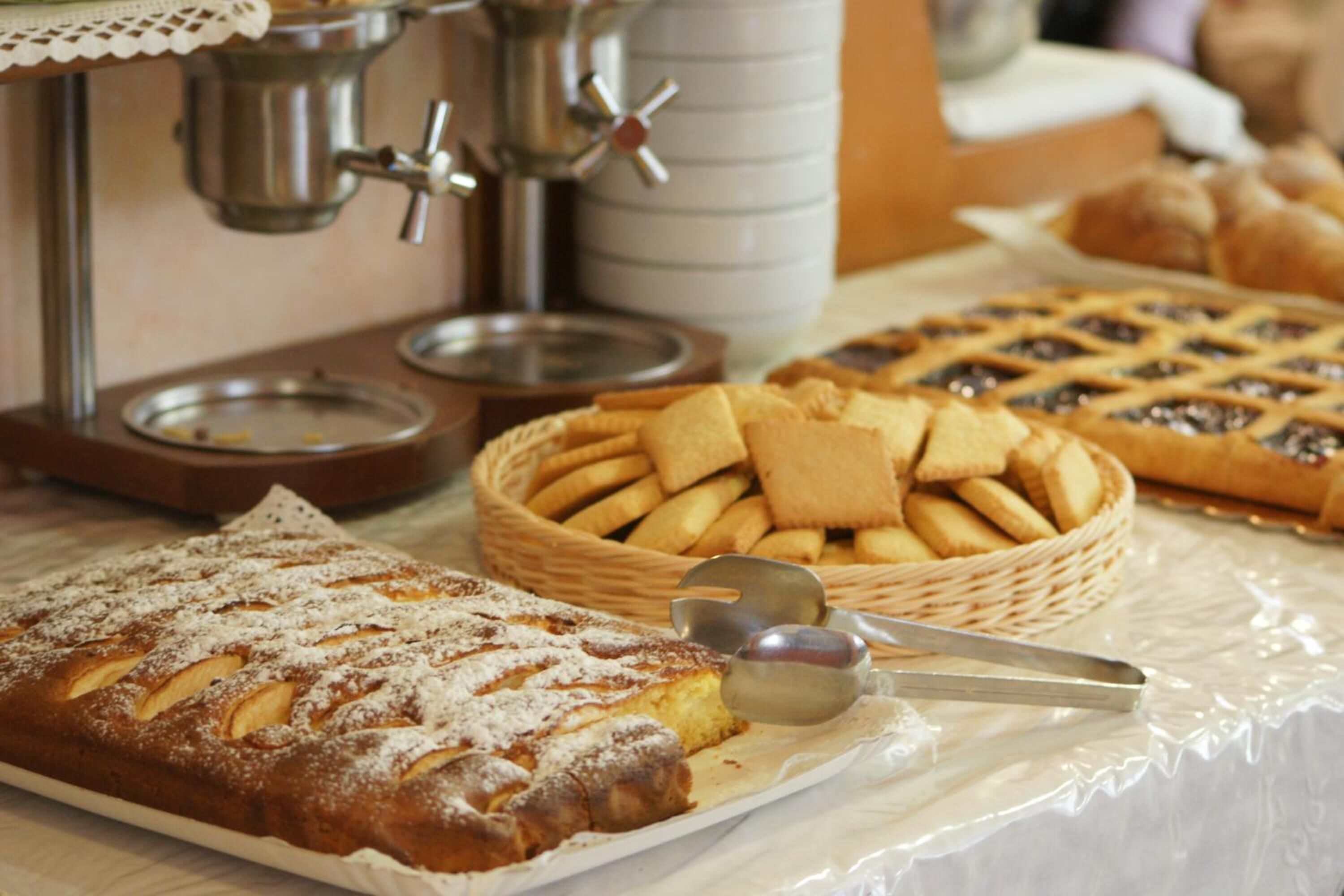 A buffet table with a variety of baked goods, including a large cake with a lattice top and a pie with a lattice crust.