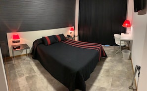 A hotel room with a bed, bedside tables, a desk, and a chair. - La Suite Hotel (Vigo)