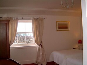 A room with a window, a bed, a bedside table, a lamp, and a painting on the wall. - Terrace Hotel (Edinburgh)