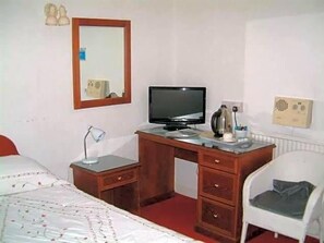 A bedroom with a wooden desk, a television, a mirror, a radiator, and a white chair. - Terrace Hotel (Edinburgh)