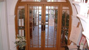 A wooden double door with glass panels, a potted plant, and a carpeted floor. - Terrace Hotel (Edinburgh)