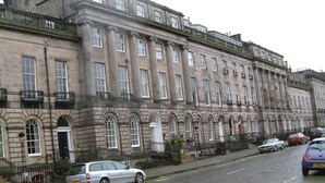 A historic building with a row of arched windows and a cobblestone street. - Terrace Hotel (Edinburgh)