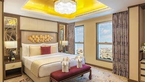 A spacious hotel room with a large bed, a chandelier, a city view, and a red bench. - Joudyan Olaya Riyadh (Riyadh)