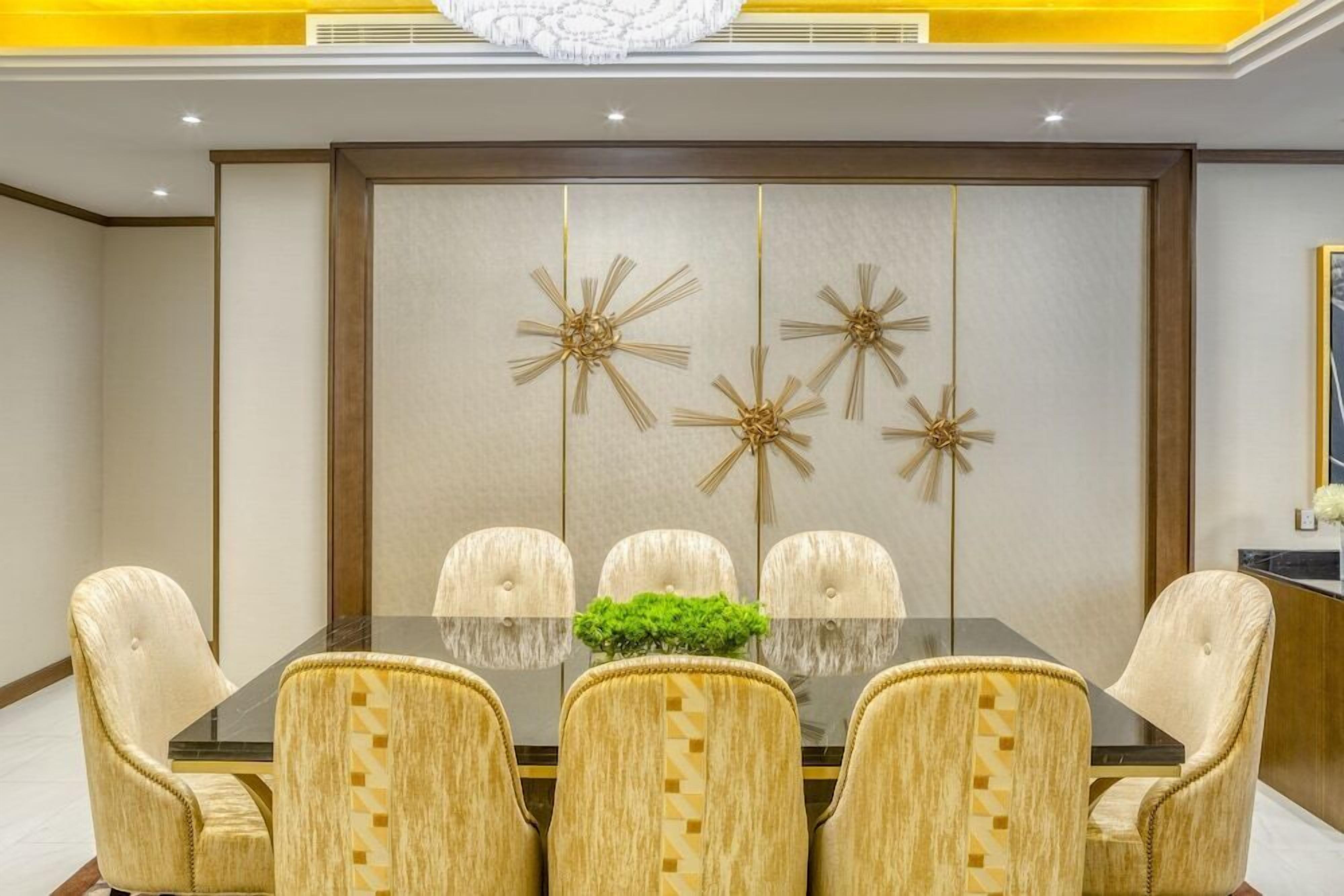 A conference room with a glass table, five upholstered chairs, and decorative wall panels.