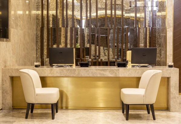 A reception desk with two computers, a gold counter, and two chairs. - Joudyan Olaya Riyadh (Riyadh)