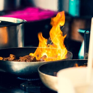 A pan on a stove with food cooking over an open flame. - Hotel Ombretta Mare (Rimini)
