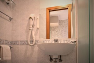 Un baño con un lavamanos blanco, un espejo y un secador de pelo montado en la pared.