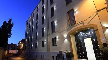 Un hotel a più piani con facciata moderna, caratterizzato da un ingresso in evidenza con una porta nera e un cartello sopra.