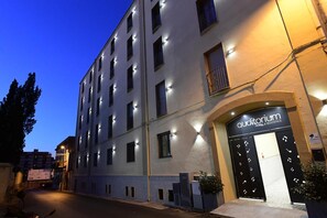 Um hotel de vários andares com fachada moderna, apresentando uma entrada destacada com porta preta e uma placa acima.