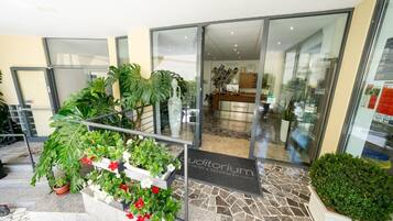 L'ingresso di un hotel con una reception, una porta in vetro e un pavimento piastrellato.