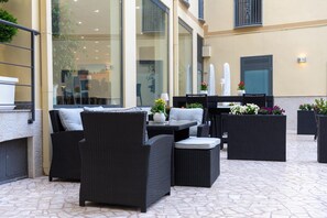 An outdoor seating area with wicker furniture, a table, and potted plants. - Hotel Auditorium (Bari)