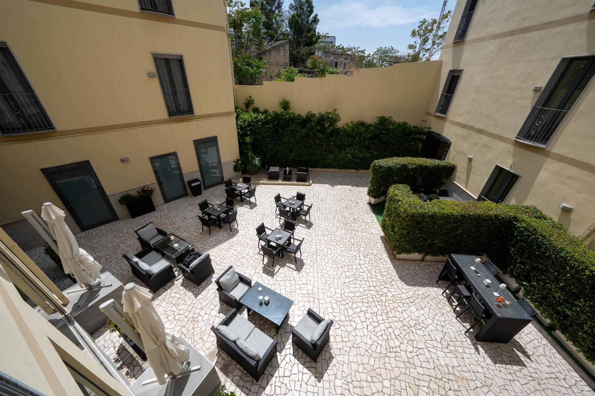 Un'area patio esterna con diversi tavoli e sedie, circondata da edifici.