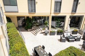 A courtyard with outdoor seating, a staircase, and a building with balconies. - Hotel Auditorium (Bari)