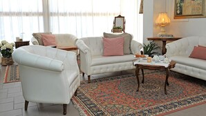A living room with a white sofa set, a patterned rug, and a wooden coffee table. - Hotel Gradara (Bellaria-Igea Marina)