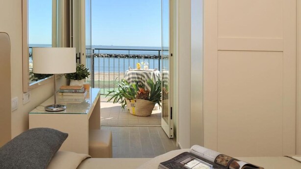 A balcony with a view of the sea, a small table with a lamp, and a chair. - Hotel Gradara (Bellaria-Igea Marina)
