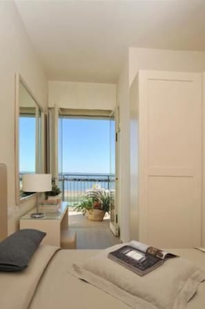 A hotel room with a balcony, a bed, a bedside table with a lamp, and a view of the sea. - Hotel Gradara (Bellaria-Igea Marina)