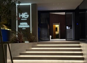 A modern hotel entrance with a neon sign, a staircase, and a glass door leading inside. - Hotel Gradara (Bellaria-Igea Marina)