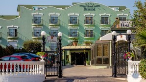 Een hotel met een groene gevel, meerdere balkons en een hekwerk.