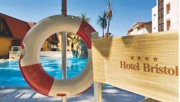 Une bouée de sauvetage près d’une piscine, avec une pancarte indiquant « Hôtel Bristol ».