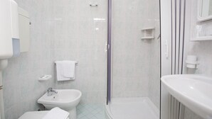 Une salle de bain moderne dotée d’une douche à parois de verre, d’un lavabo sur colonne et de toilettes séparées.