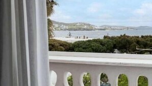 A balcony with a view of the sea, a table with a glass of juice and pastries, and a chair. - Galation Hotel Mykonos (Mykonos)