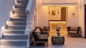 A staircase leading to a lobby with wicker furniture and a decorative wall. - Galation Hotel Mykonos (Mykonos)