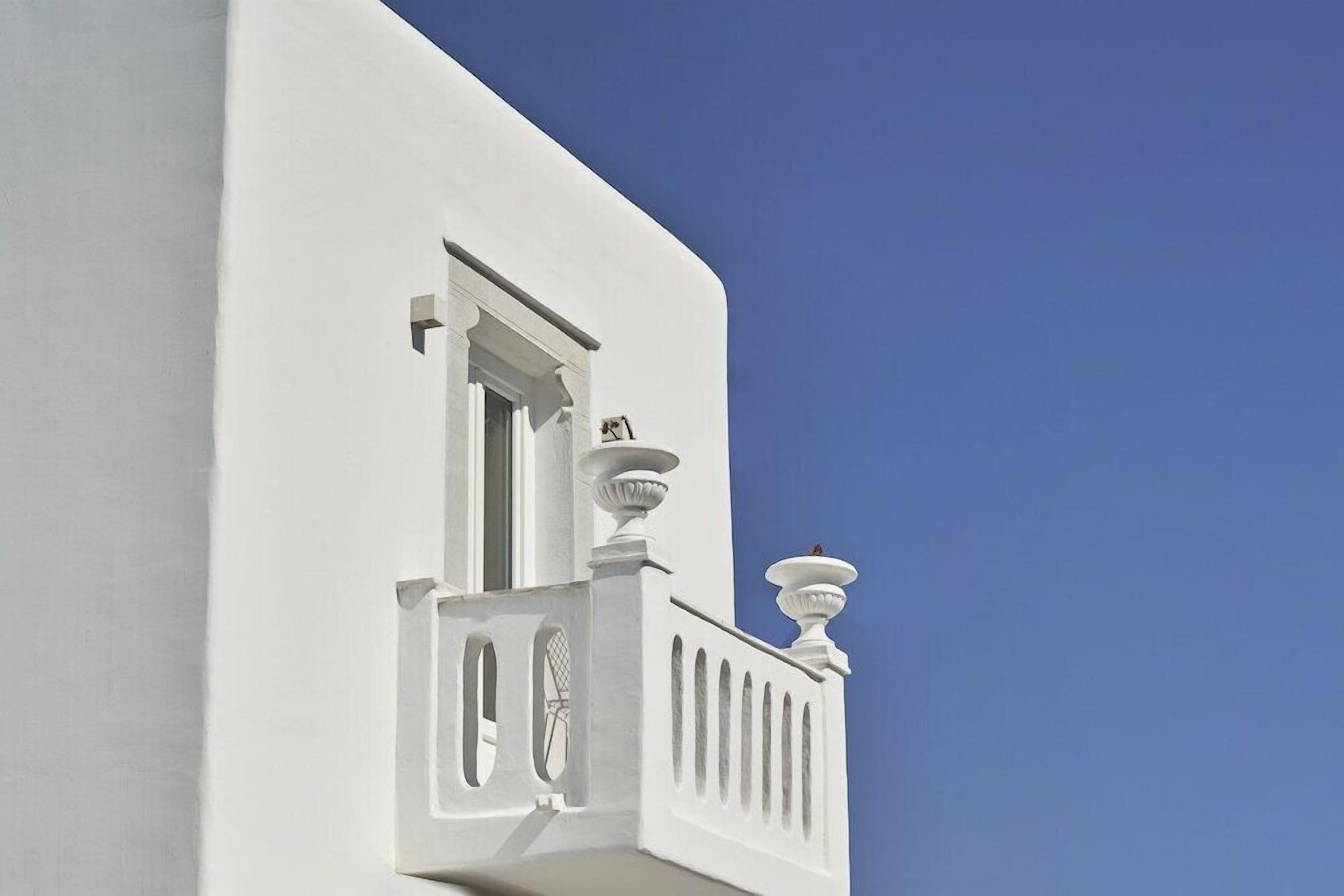 A white building with a balcony and a window.