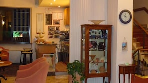 Ein Wohnzimmer mit einer Couch, einem Couchtisch, einer Zimmerpflanze, einem Holzschrank mit Glastüren und einer Wanduhr.