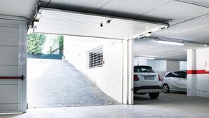 Autotalli, jossa on betonilattia, valkoinen tallinovi ja sen sisällä oleva auto.