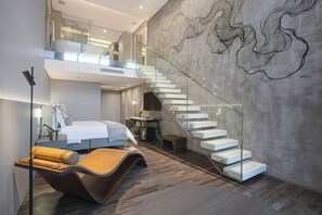 A modern interior with a staircase, a bed, a desk, and a lounge chair. - Suryaa Hotel Pinhais (Pinhais)