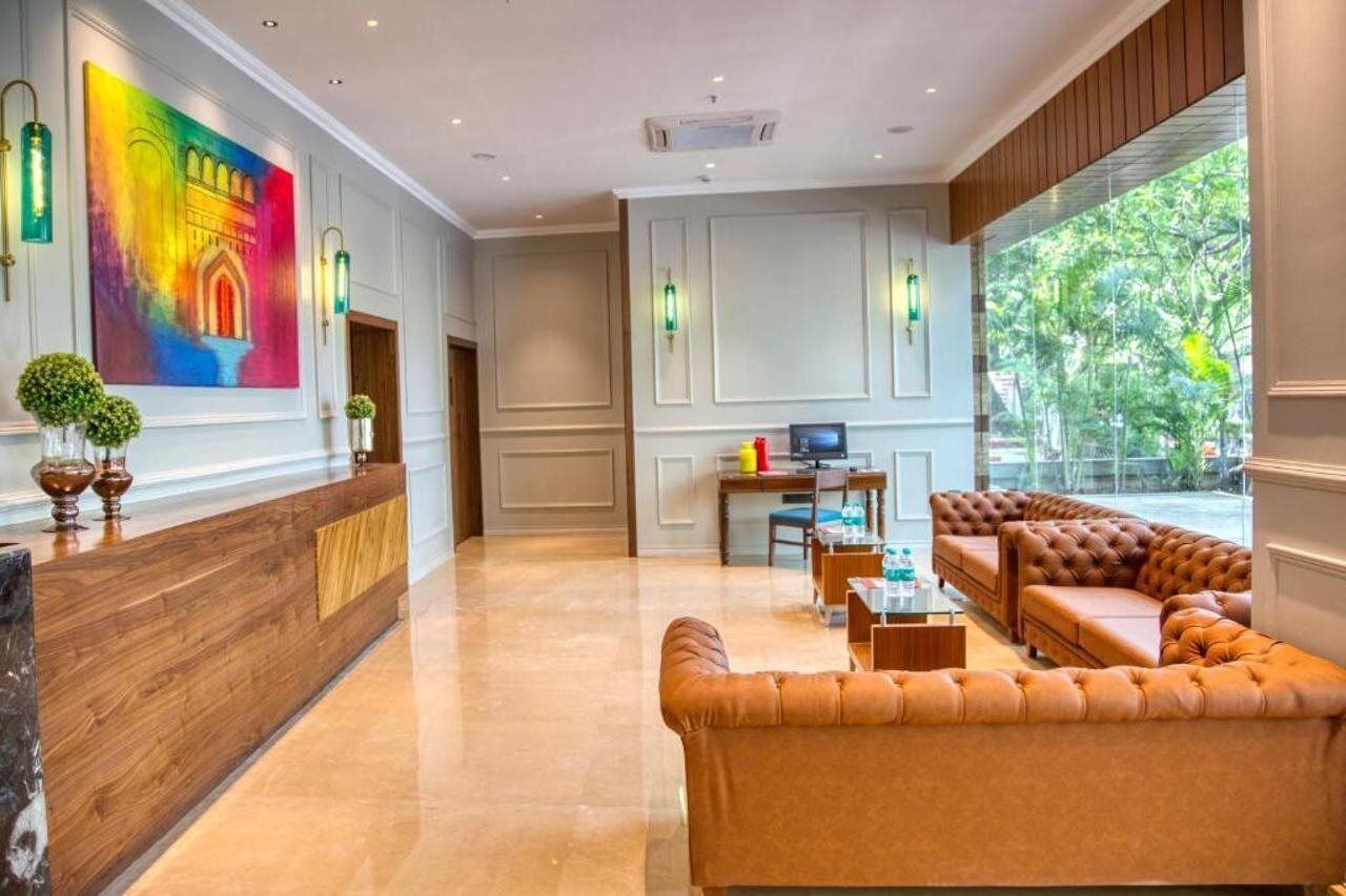 A modern lobby with a reception desk, seating area, and large windows offering a view of greenery.