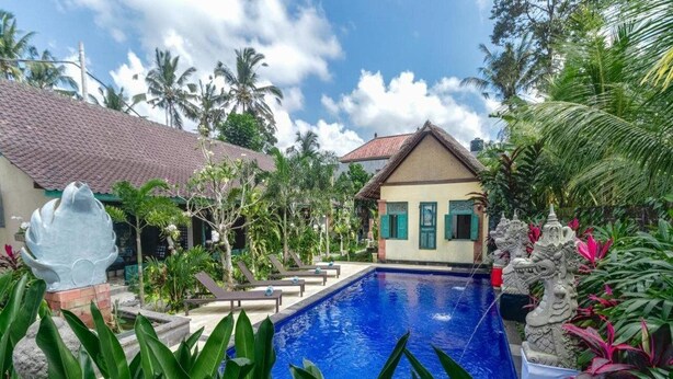 A swimming pool surrounded by tropical plants and a small building with a tiled roof. - Nawa Sakti Resort (Ubud)