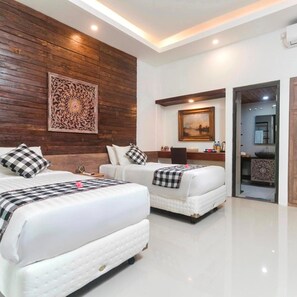 A hotel room with two beds, a wooden accent wall, a painting, and a bathroom visible through an open door. - Nawa Sakti Resort (Ubud)