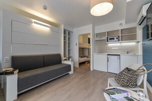A compact living space with a sofa, kitchenette, and a small dining area.