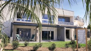 Un edificio moderno de dos pisos con un patio cubierto, piscina y un cartel que indica que es zona de refugio.