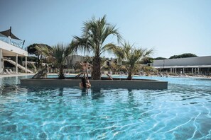 Ein Pool mit Palmen und Liegestühlen, umgeben von modernen Gebäuden.
