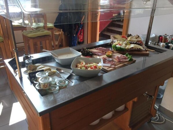 Un buffet proposant une variété de plats, notamment des viandes, des salades et des desserts.